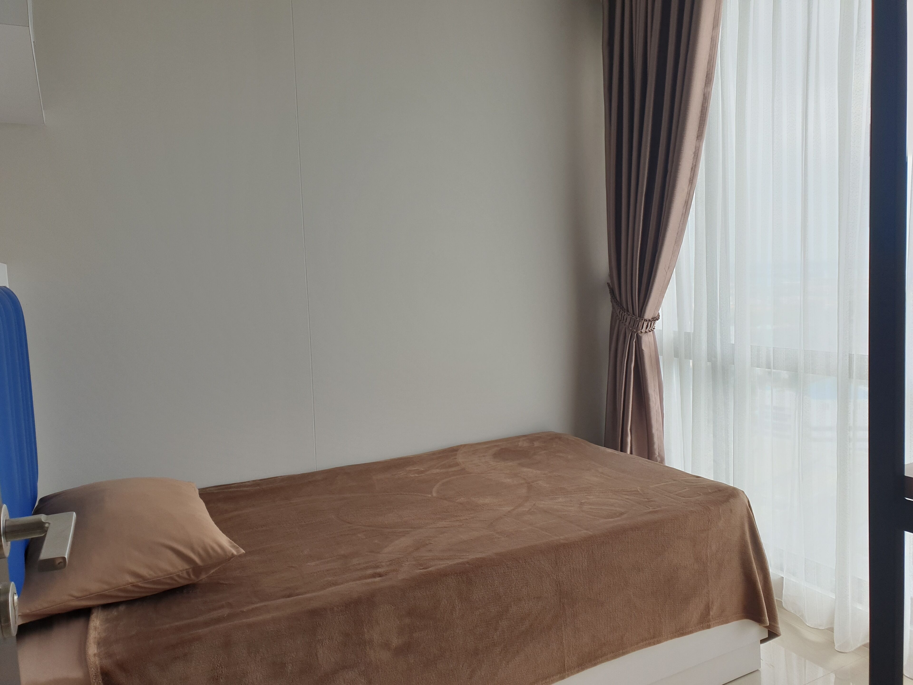 A single bed with a brown cover, a pillow, and a metal headboard.