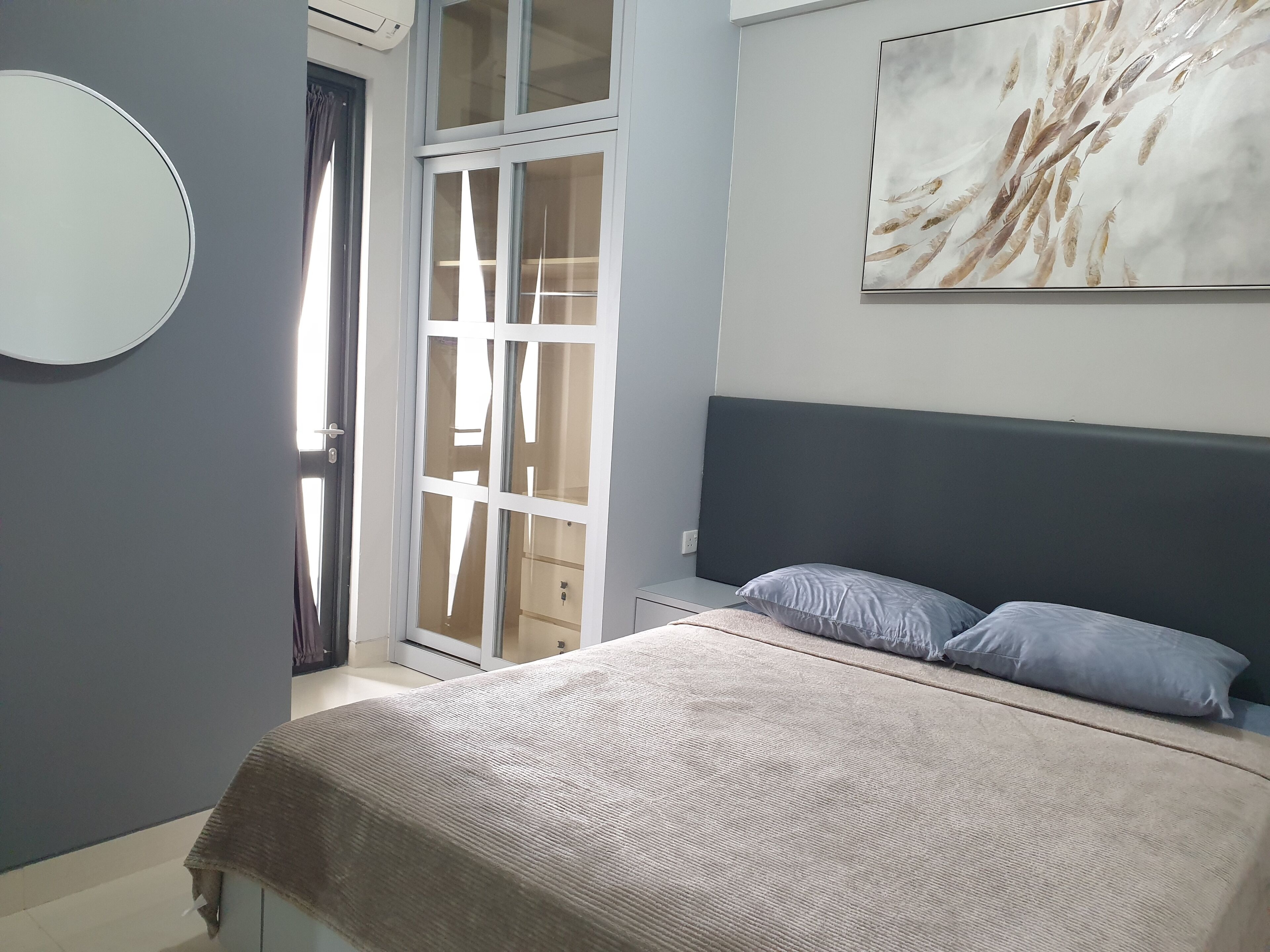 A bedroom with a bed, a headboard, a wall-mounted artwork, and a sliding glass door leading to a balcony.