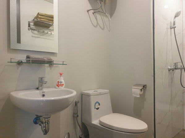 A bathroom with a white sink, toilet, and glass-enclosed shower.