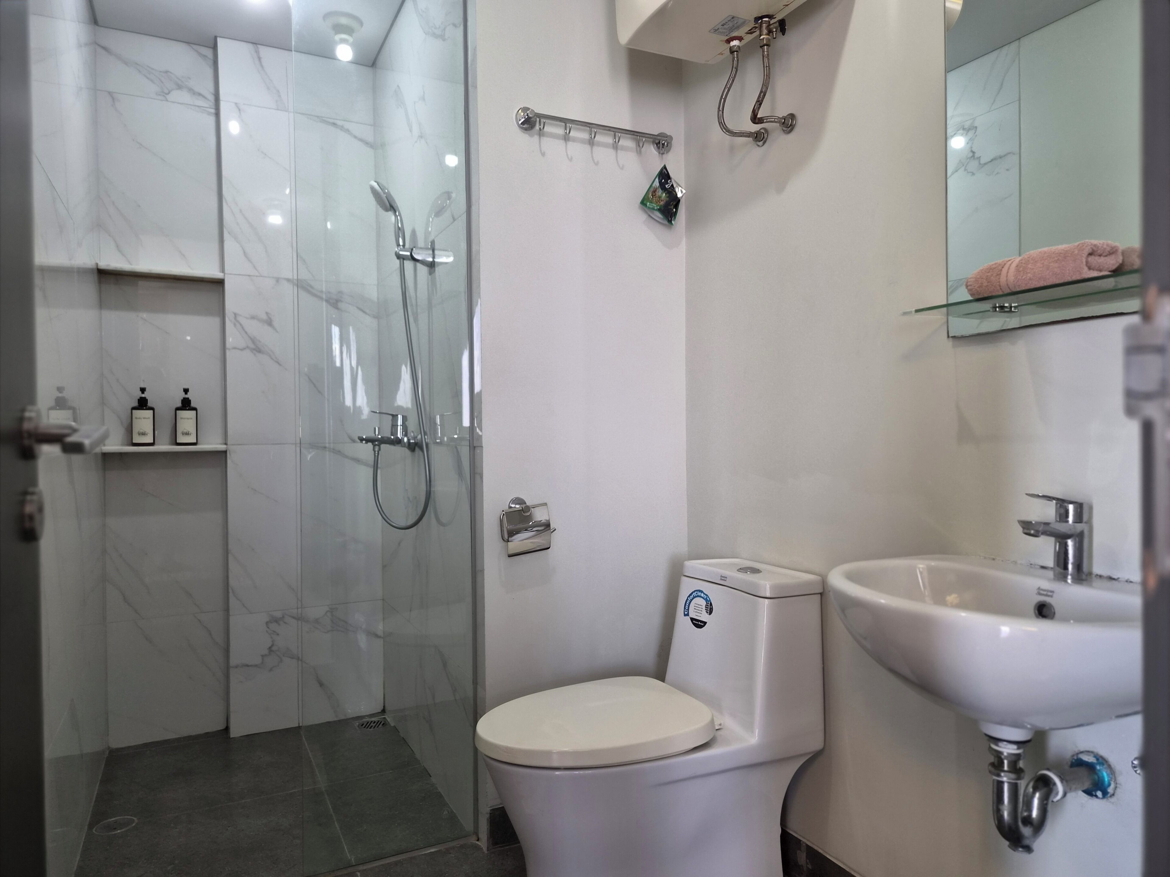 A modern bathroom with a glass-enclosed shower, a white toilet, and a sink with a mirror above it.