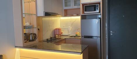 A modern kitchen with a built-in microwave, stainless steel refrigerator, and a glass island counter.