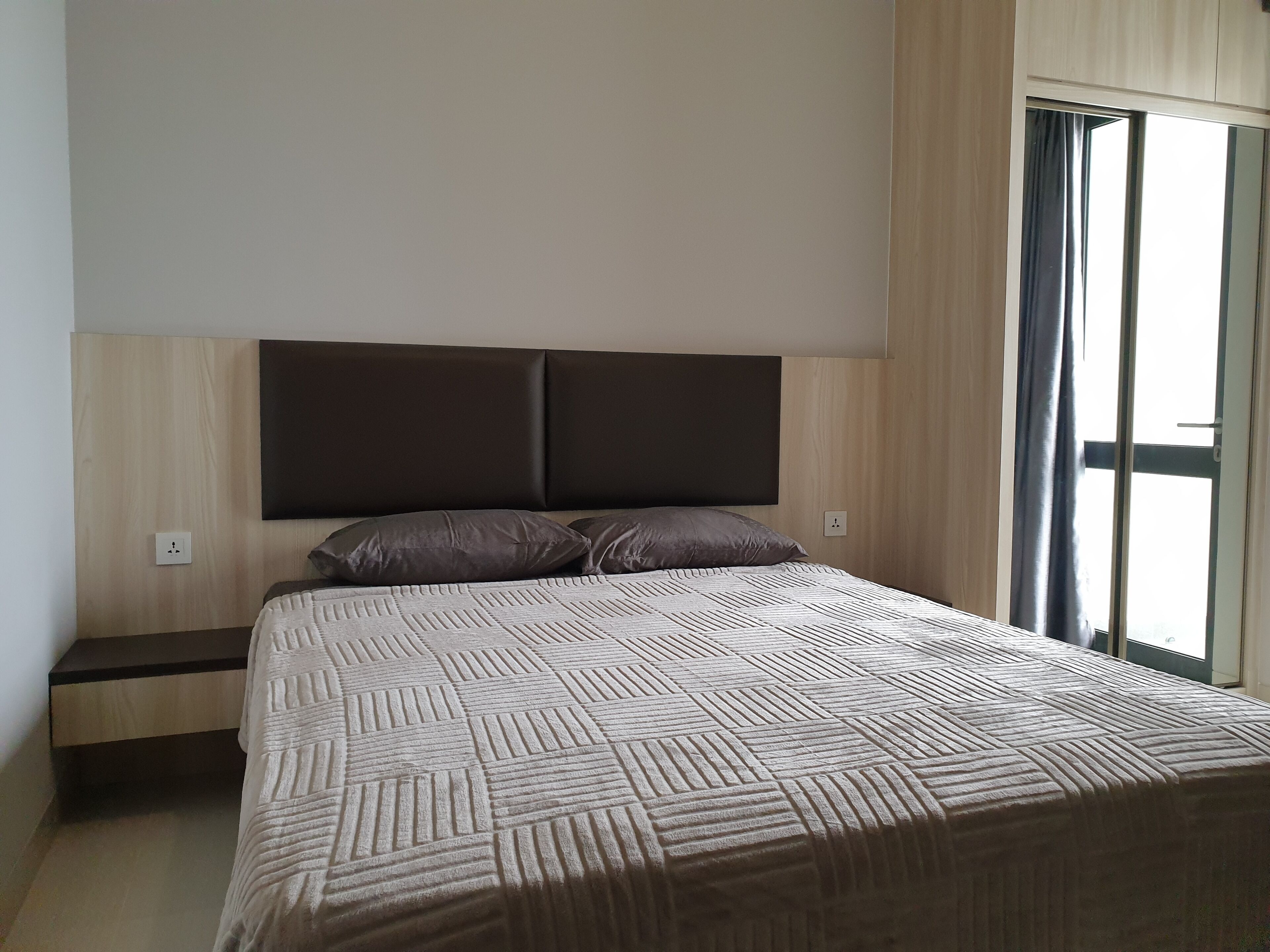A bedroom with a bed, a nightstand, and a window with curtains.