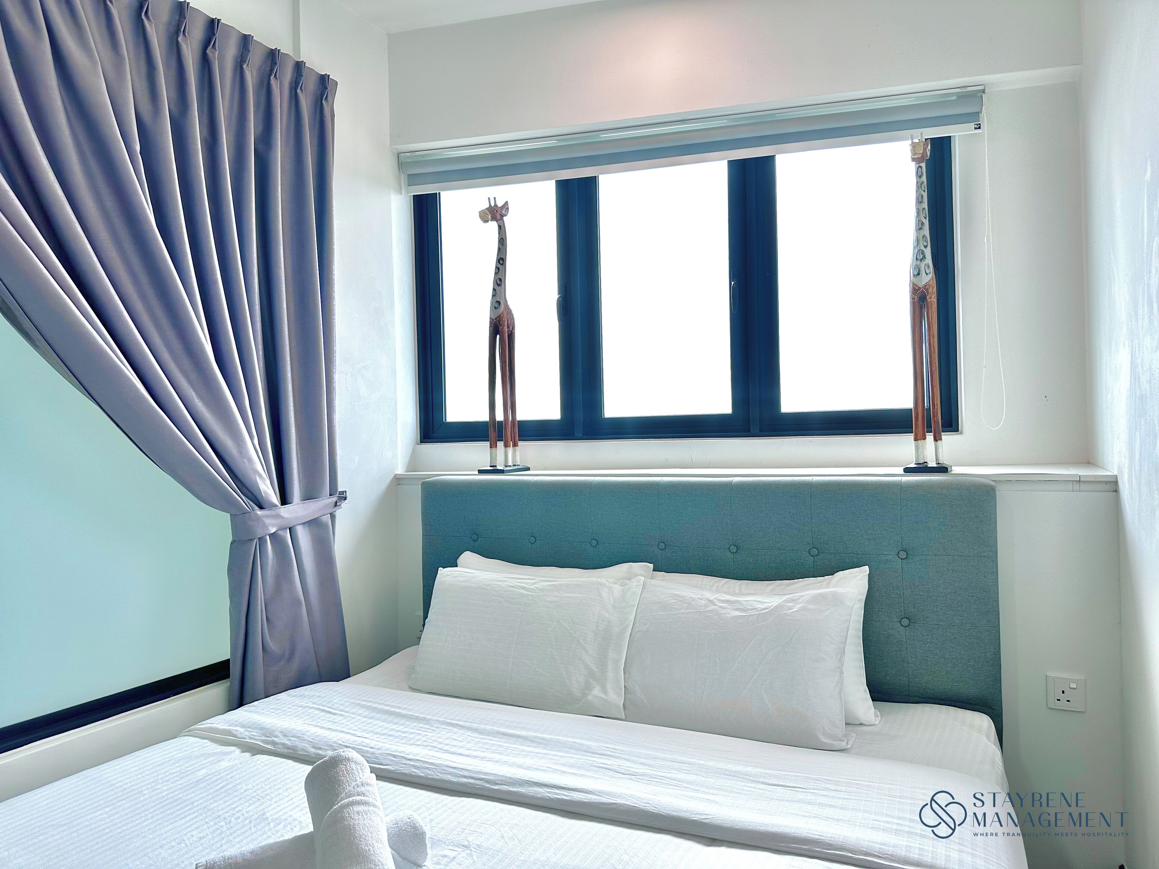 Ein Hotelzimmer mit Bett, Fenster mit Vorhängen und Kopfteil.