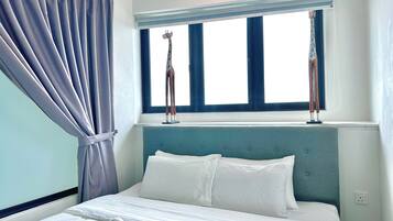 Ein Hotelzimmer mit Bett, Fenster mit Vorhängen und Kopfteil.