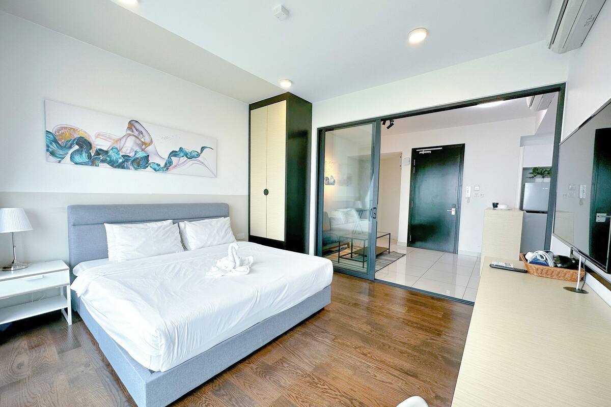 Una habitación de hotel moderna con una cama grande, un escritorio y un ventanal corredero que da a un balcón.