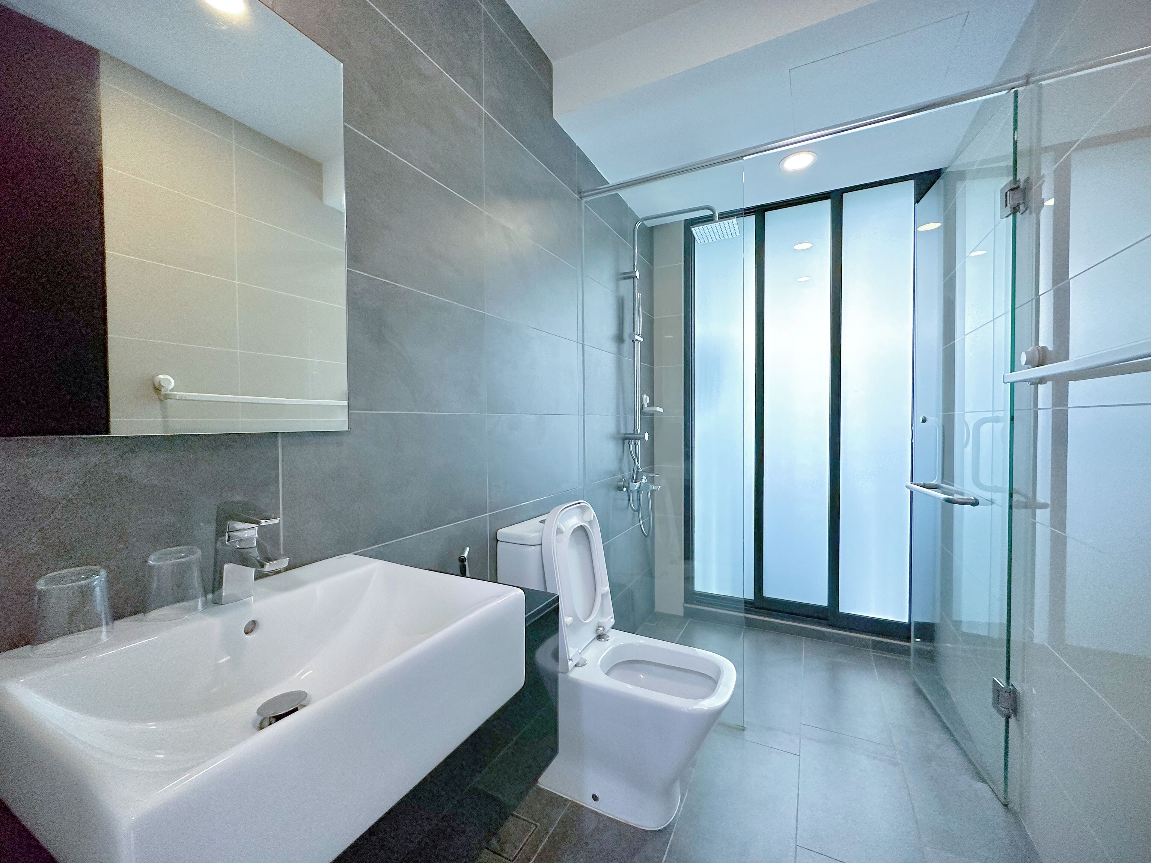 A modern bathroom with a large white bathtub, a toilet, and a glass-enclosed shower area.