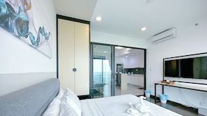 Une chambre d’hôtel moderne dotée d’un grand lit, d’une télévision à écran plat, d’un bureau et offrant une vue sur la cuisine et le balcon.