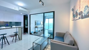 Un salon moderne avec une table basse en verre, un canapé et une vue sur un balcon.