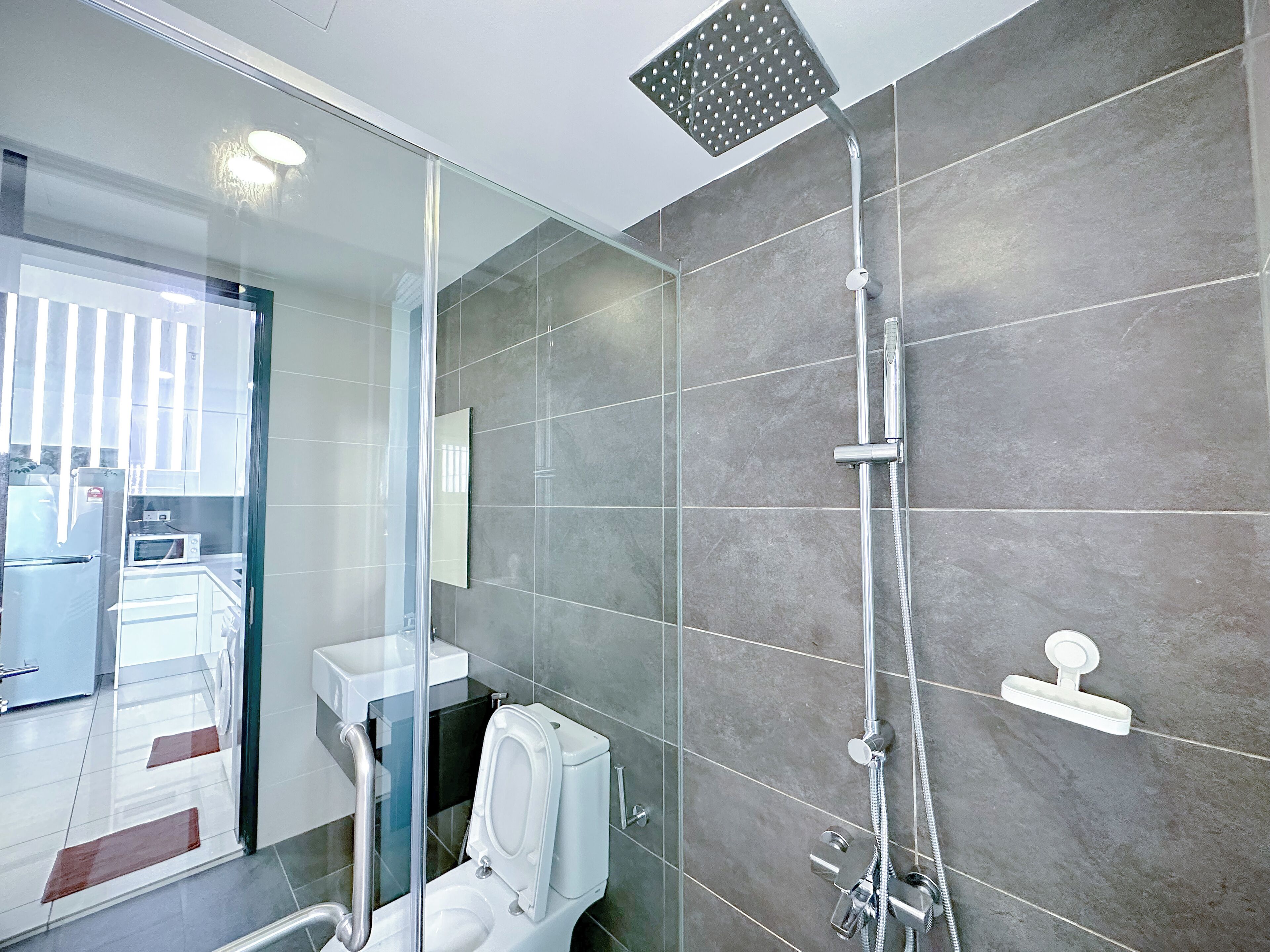 Een moderne badkamer met een douchecabine van glas, een toilet en een wastafel.