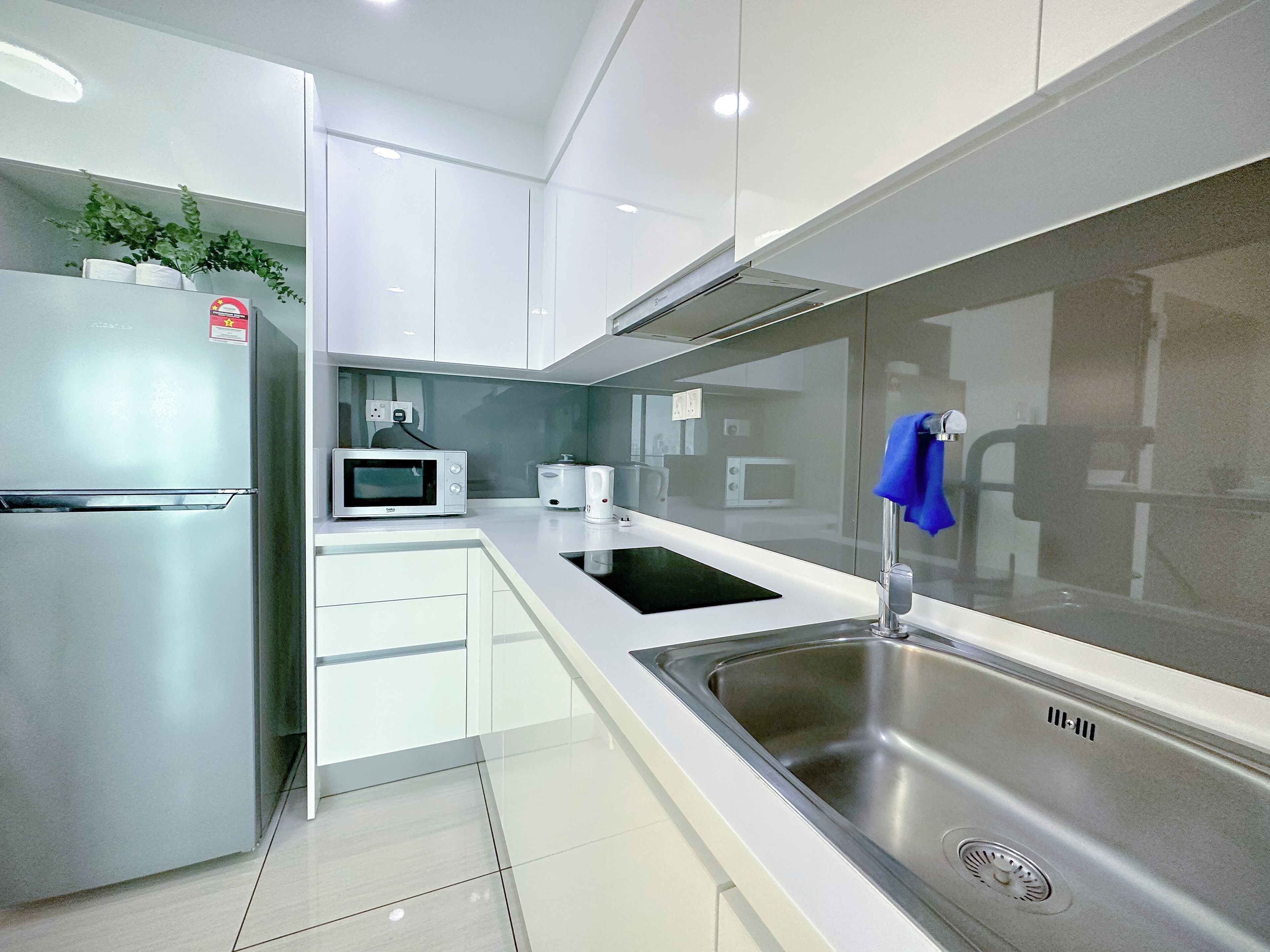 Una cocina moderna con armarios blancos, electrodomésticos de acero inoxidable y encimera negra.