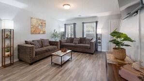 A living room with two sofas, a coffee table, and a potted plant.