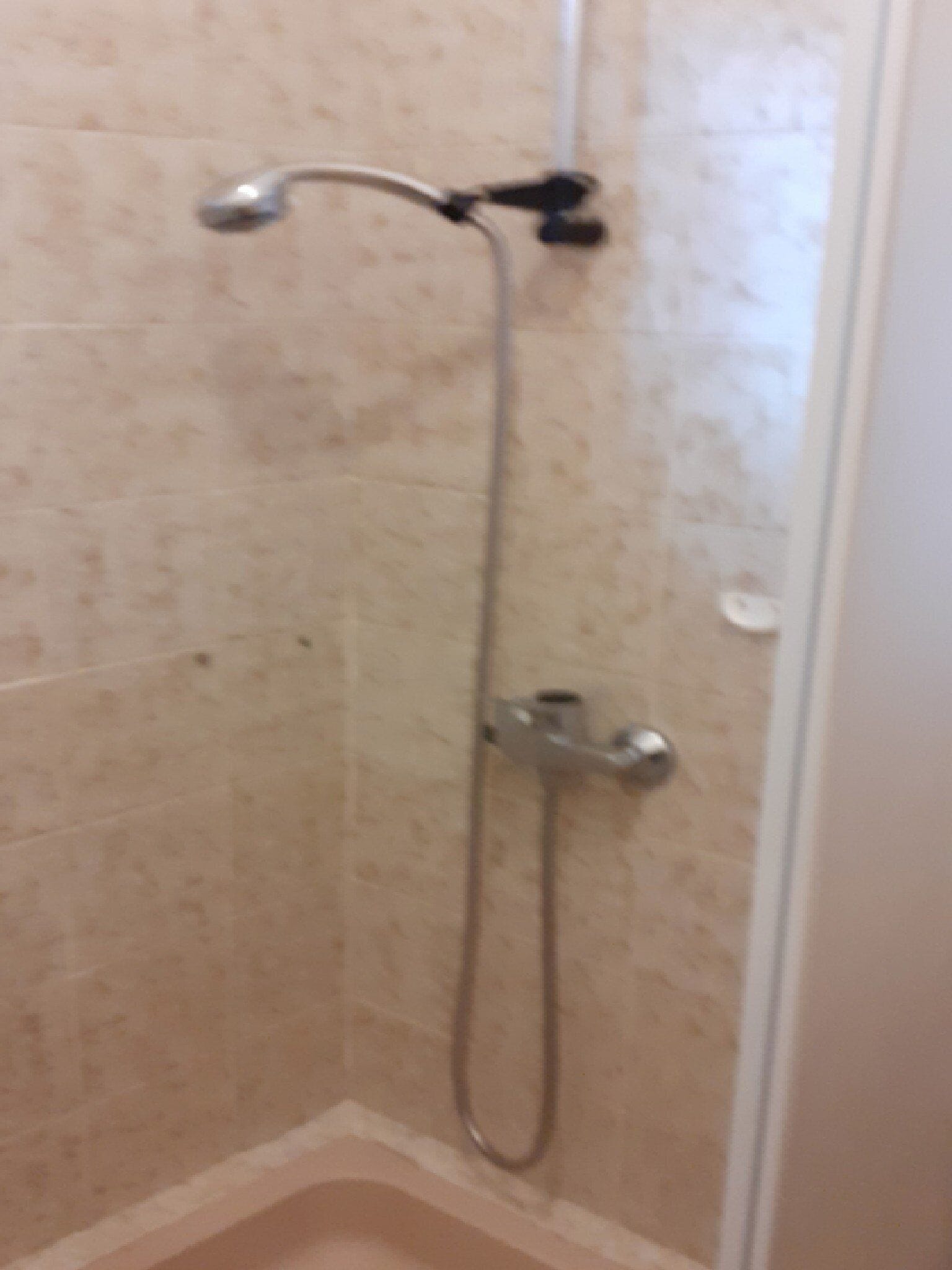 Brusebad med håndbruser og vandhane på væggen.