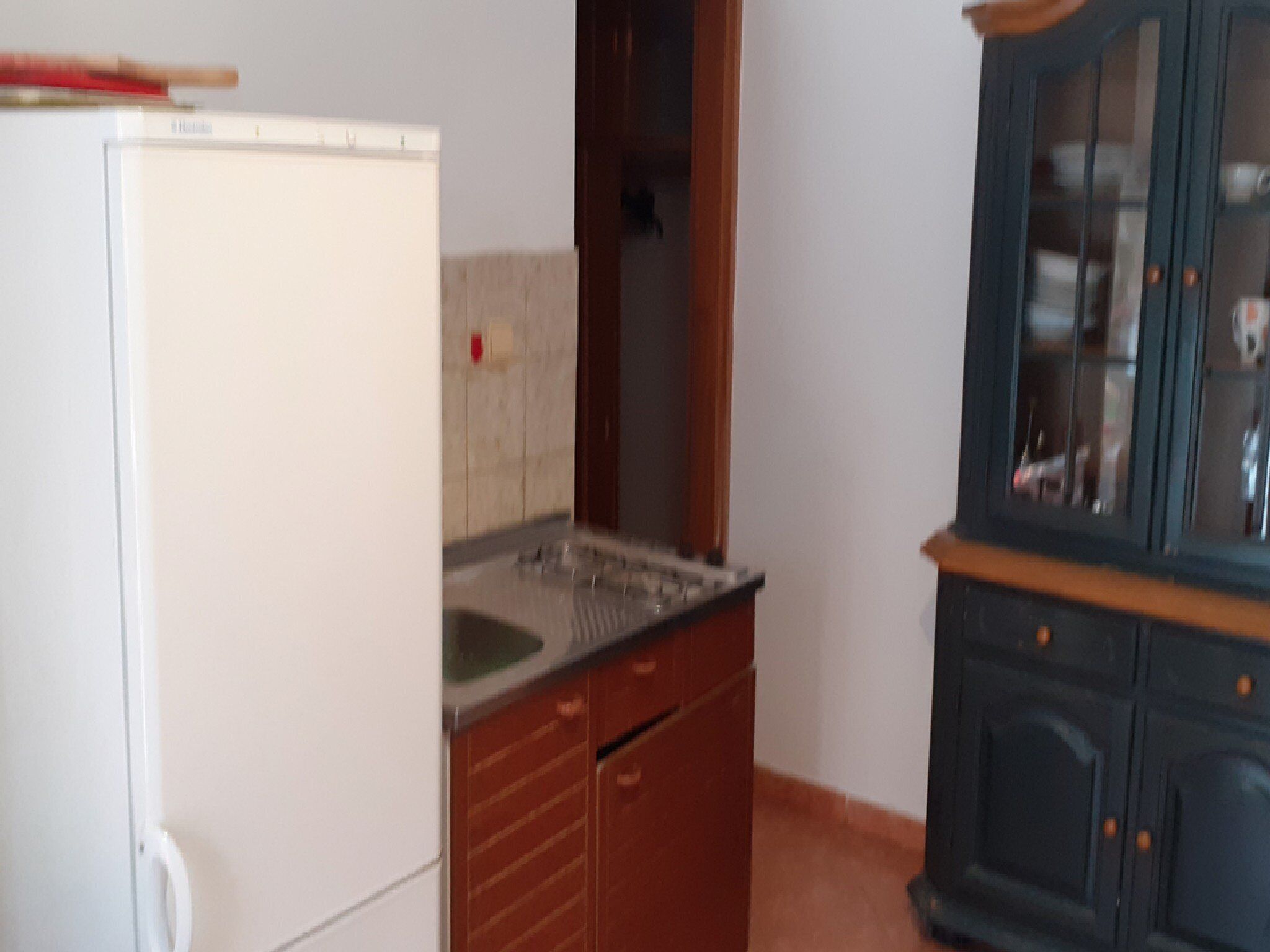 Una cocina con un refrigerador blanco, armarios de madera y un mueble de madera oscura con puertas de cristal.