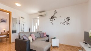 Ein modernes Wohnzimmer mit einer Couch, einem kleinen Beistelltisch und einem Fernseher.