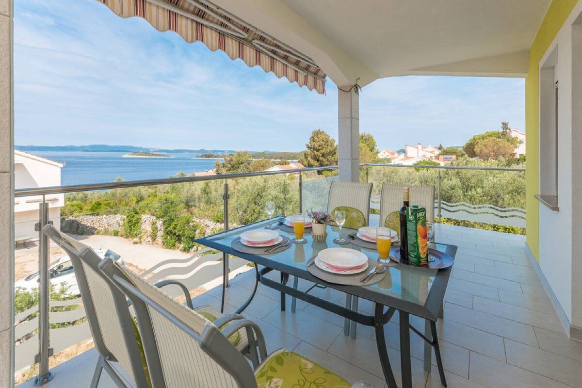 Un balcon avec une table dressée pour deux personnes, offrant une vue panoramique sur la côte.