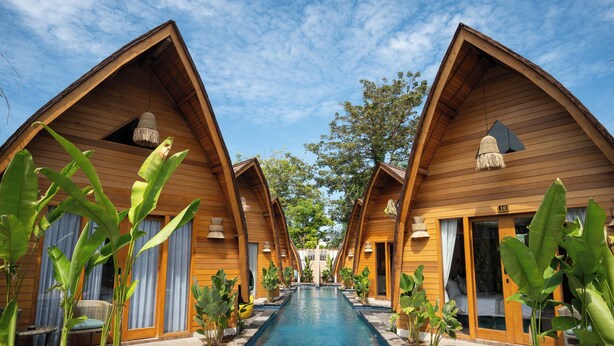 A row of wooden bungalow-style accommodations with a central swimming pool. - Abian Klumpu Villa & Spa Sanur Bali (Denpasar)