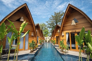 A row of wooden bungalow-style accommodations with a central swimming pool.