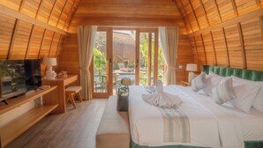 A cozy, wooden-paneled room with a bed, a desk, a television, and a view of a pool and greenery outside. - Abian Klumpu Villa & Spa Sanur Bali (Denpasar)