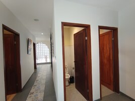 A hallway with wooden doors, a tiled floor, and a view into a bathroom.