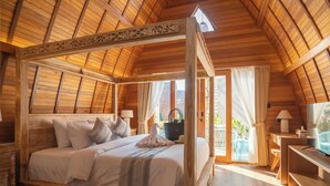 Una cama con dosel de madera, una mesita de noche y una silla.