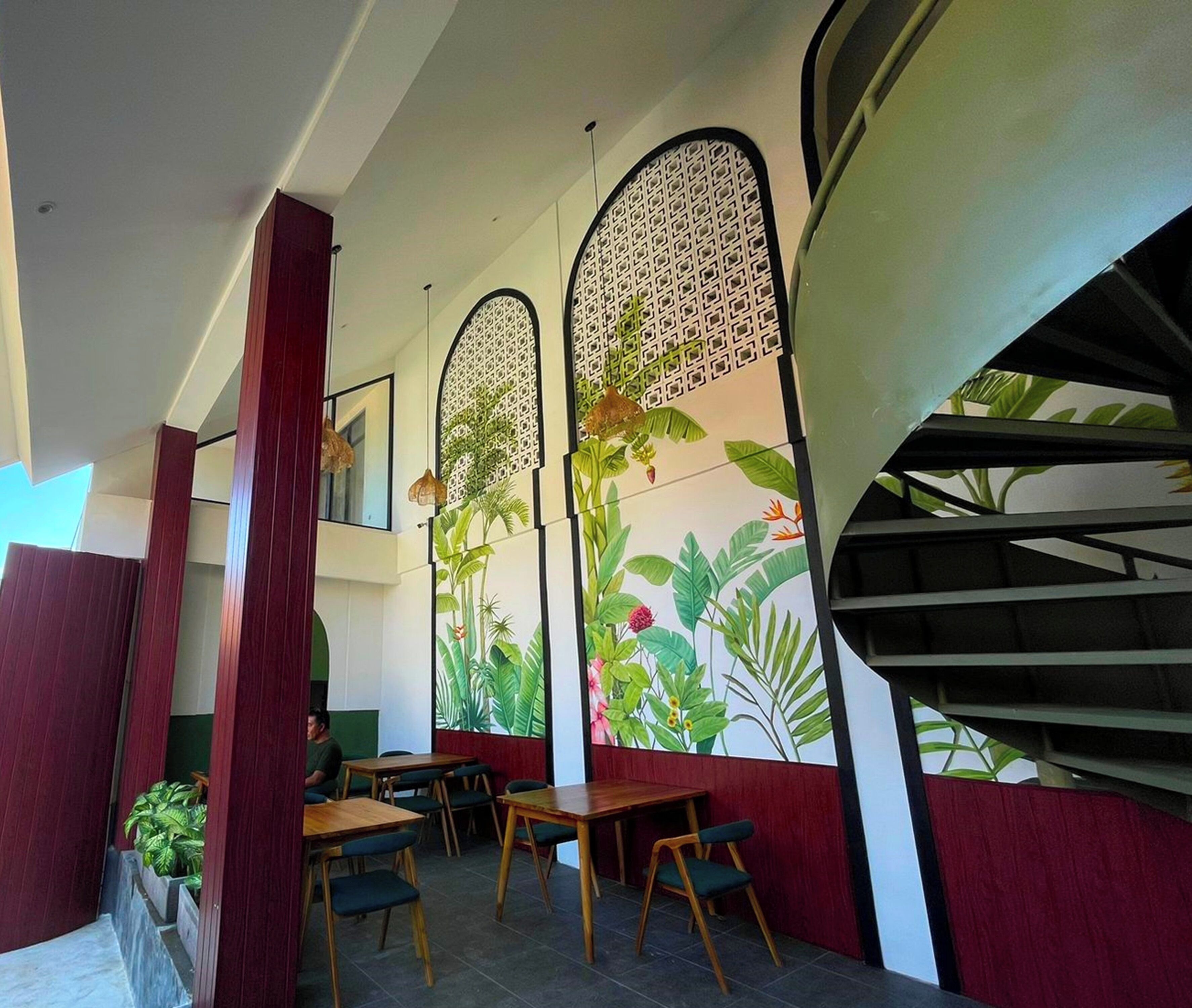 A restaurant with high ceilings, wooden tables, and chairs, and a staircase with a modern design.