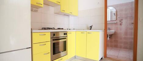 Una cocina con gabinetes amarillos, un horno de acero inoxidable y un refrigerador blanco.