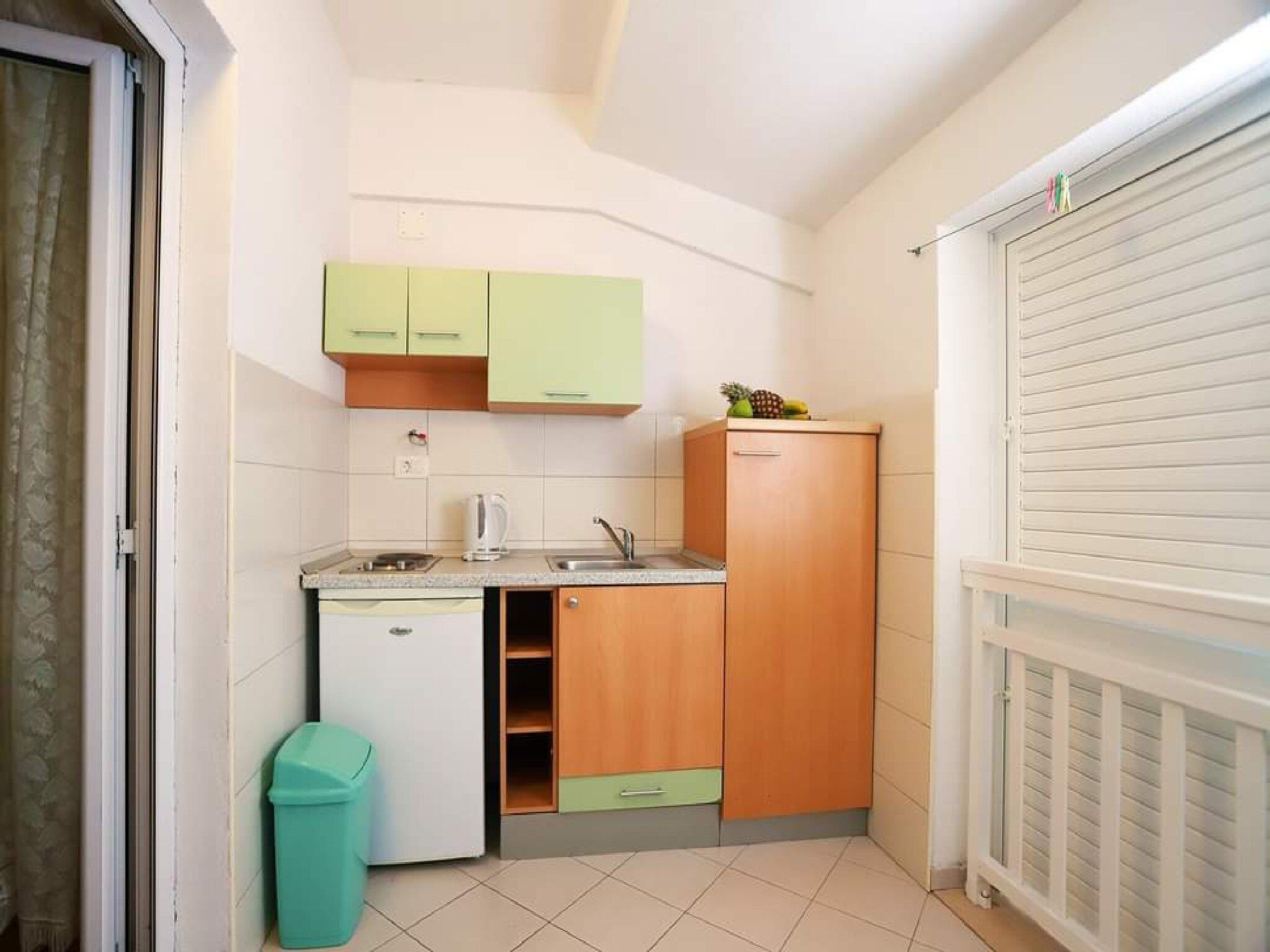 A compact kitchen with a refrigerator, sink, and wooden cabinets.
