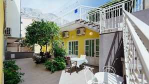 A courtyard with outdoor seating, a staircase, and a mountain view. - Apartments Pezo (Baska Voda)