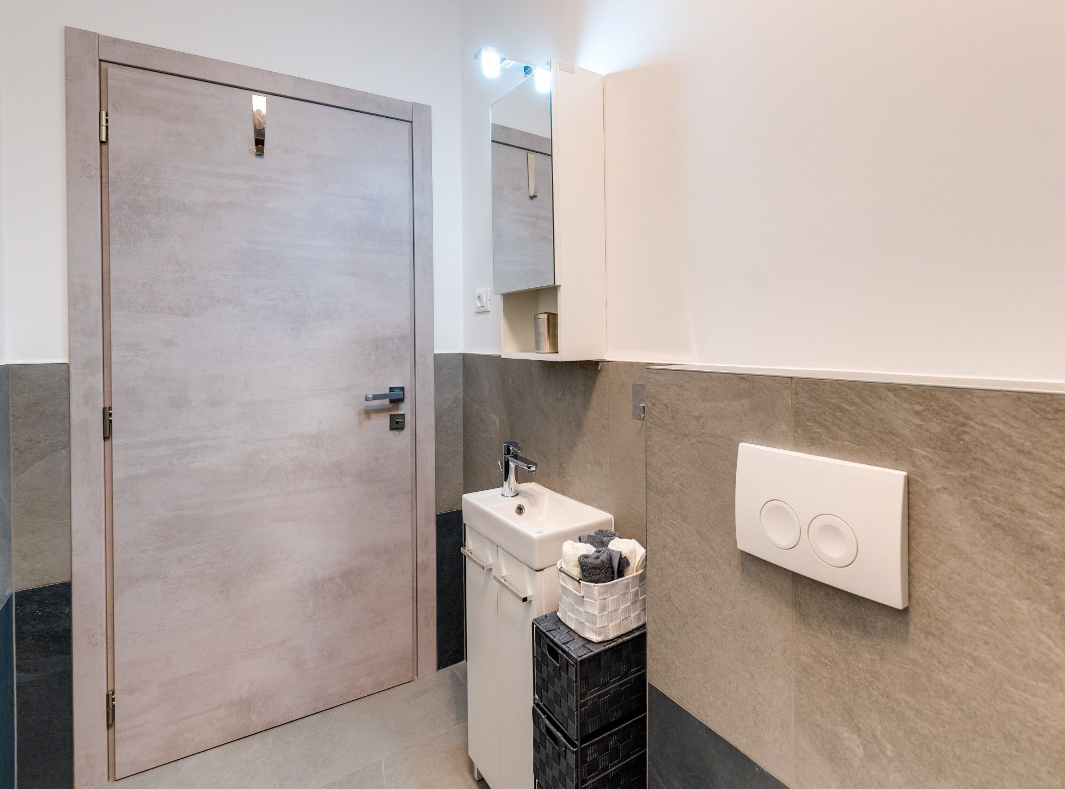 A bathroom with a wooden door, a sink, a mirror, and a towel rack.