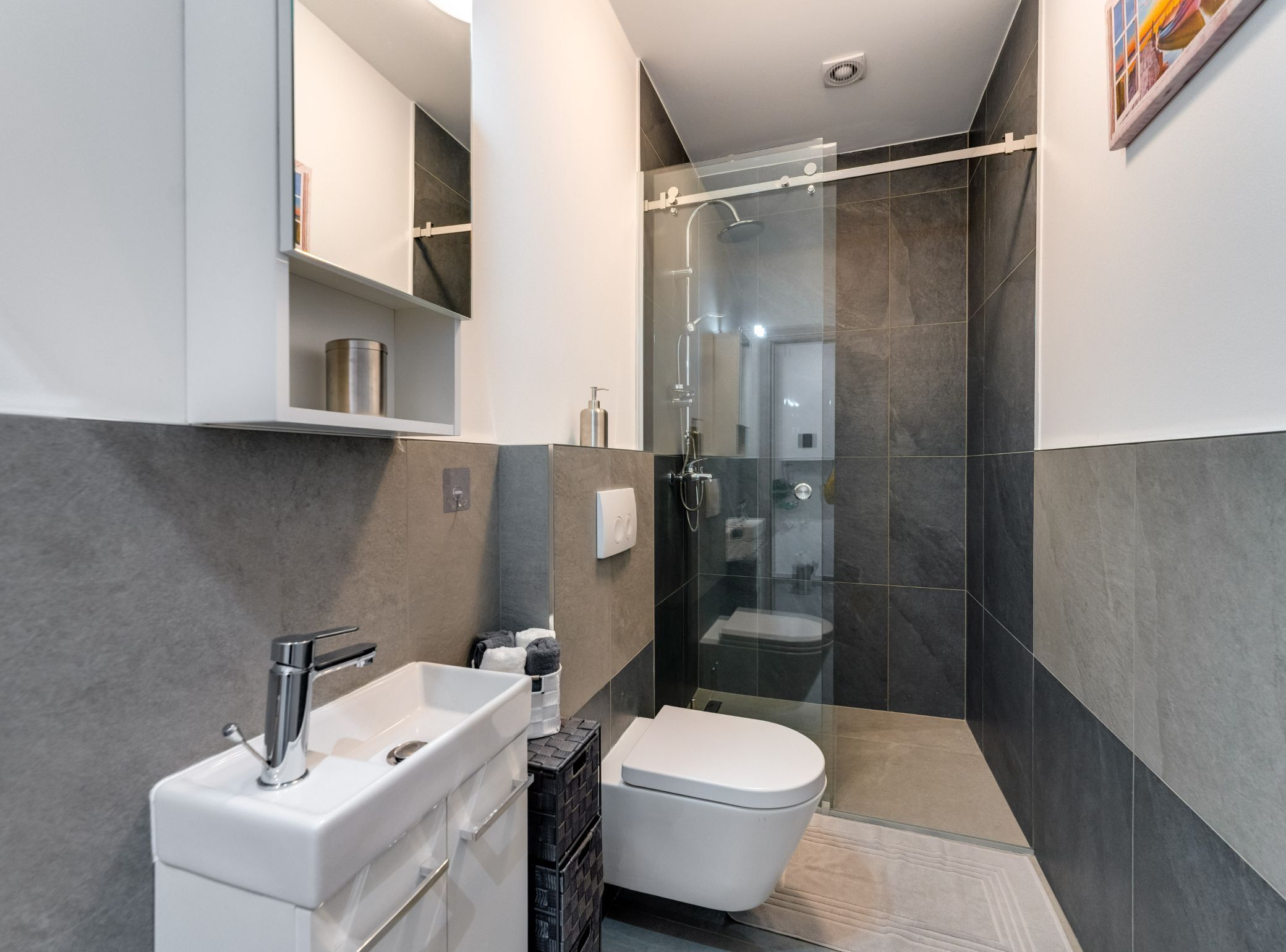 A modern bathroom with a glass-enclosed shower, a white sink, and a toilet.