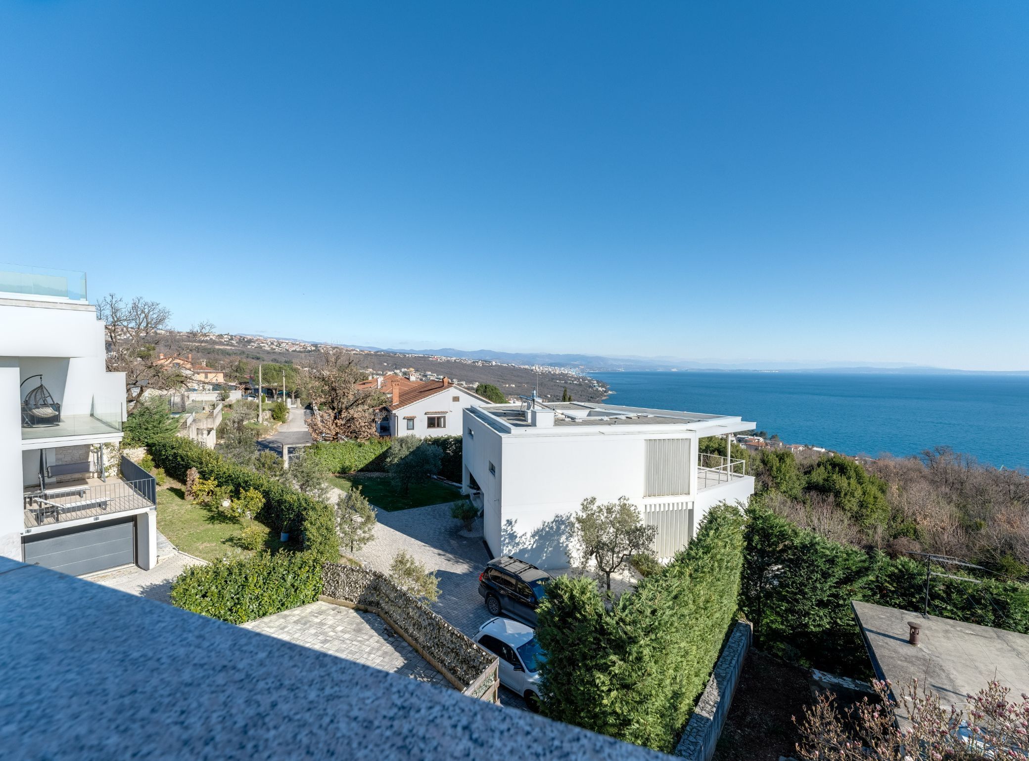 A modern residential area with a view of the sea, featuring contemporary architecture and a clear sky.