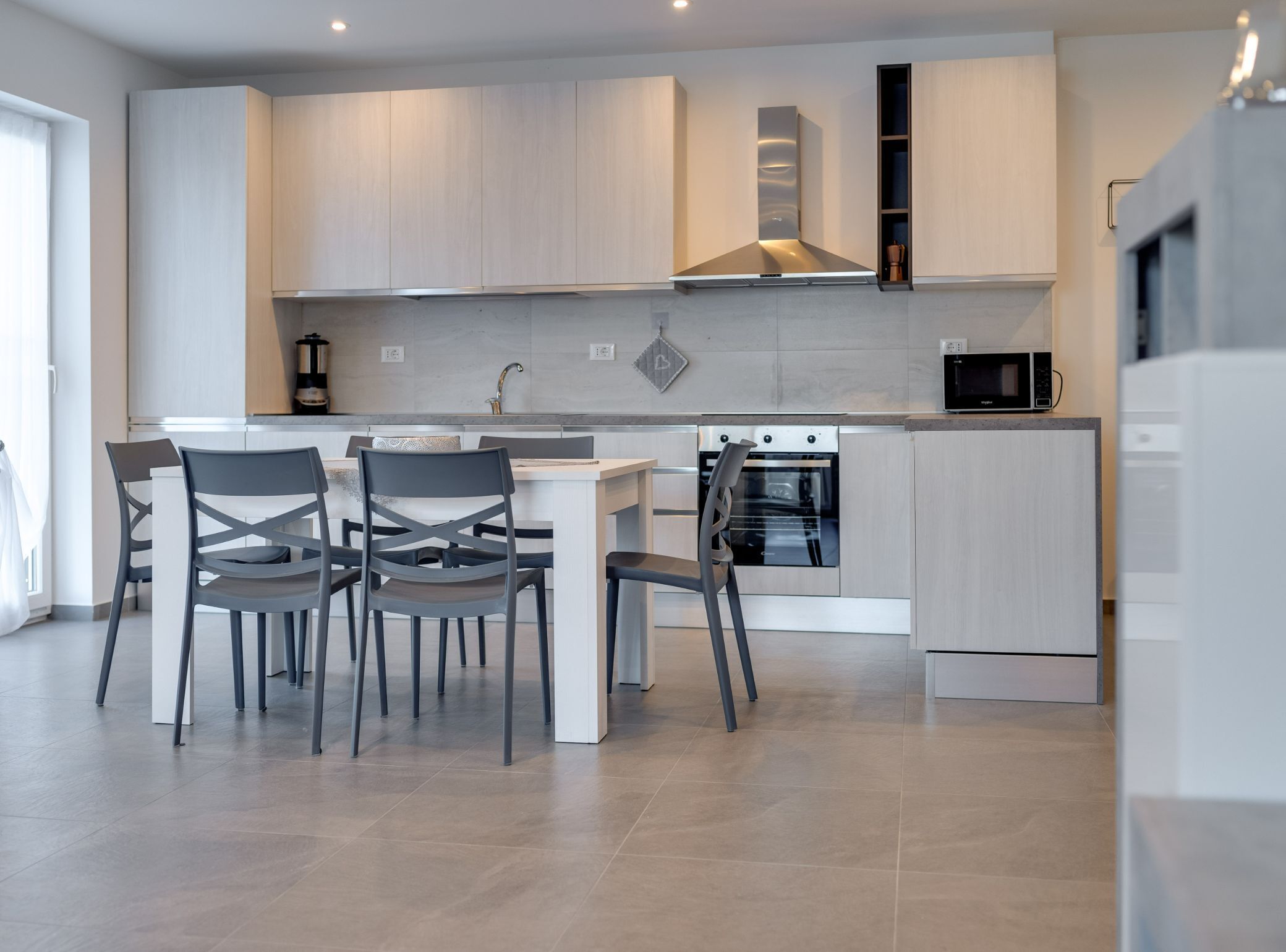 A modern kitchen with a central island, built-in oven, and a microwave.
