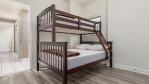 Ein Stockbett mit Holzrahmen und weißer Bettwäsche in einem Zimmer mit hellem Holzboden und weißen Wänden.