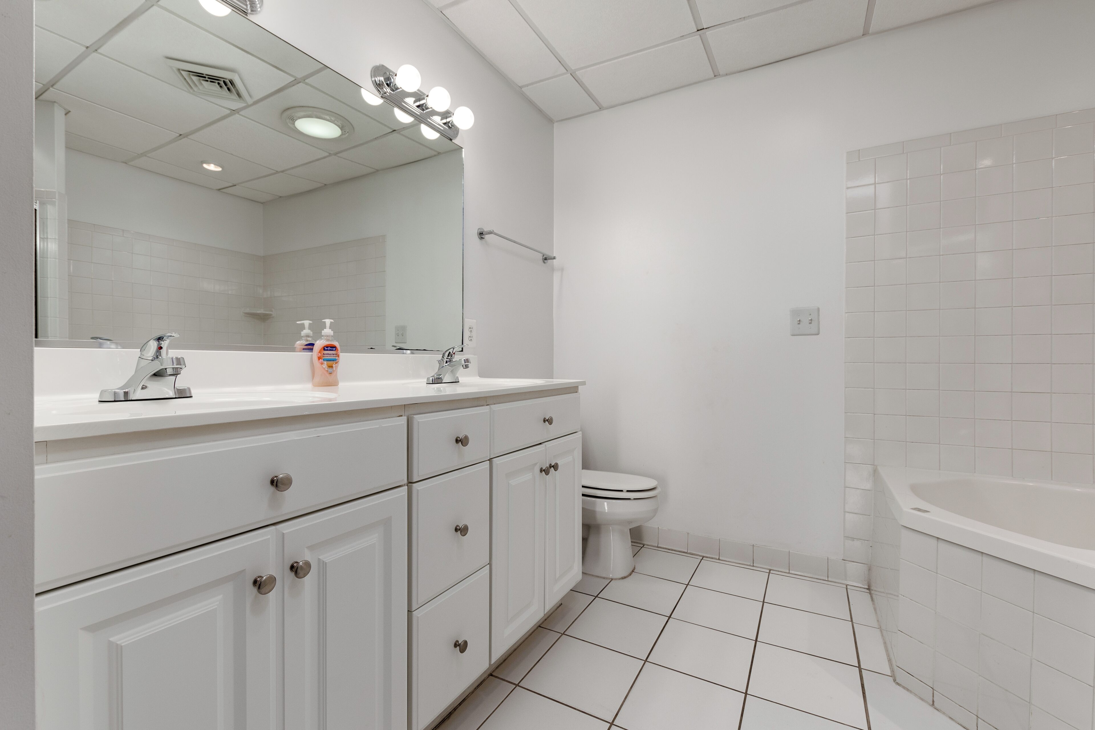 Een moderne badkamer met een wit wastafelmeubel, een toilet en een bad.