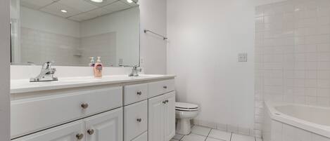 A modern bathroom with a white sink, vanity, and mirror, a toilet, and a bathtub.