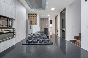 Una cocina moderna con estufa a gas central, horno integrado y microondas.