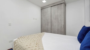 Un dormitorio con cama, armario y una lámpara en el techo.