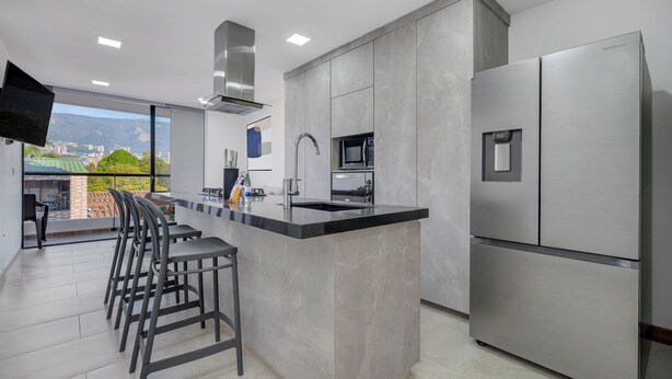 Una cocina moderna con una isla grande, electrodomésticos de acero inoxidable y vistas a la ciudad.