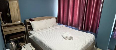 Une chambre d’hôtel avec un lit, une table de chevet, un miroir, une armoire et une fenêtre avec des rideaux.