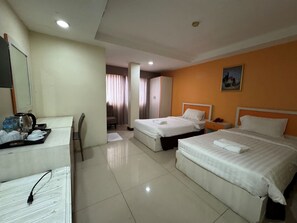 A hotel room with two beds, a desk with a coffee maker, a chair, and a painting on the wall. - ORCHID INN  at  SKV 3 (Bangkok)