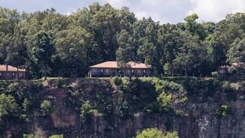 A row of buildings on a cliff with dense forest in the background.
