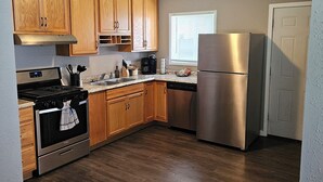 A modern kitchen with wooden cabinets, stainless steel appliances, and a wooden floor. - Modern 3BD/2BA near U of I with a large master suite! (Champaign)