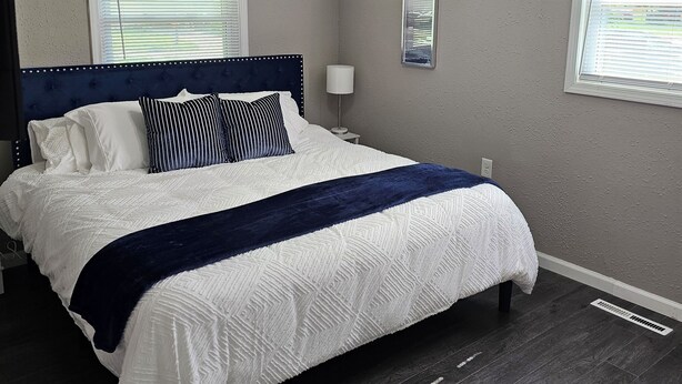 A bedroom with a bed, ceiling fan, two windows with blinds, and a nightstand with a lamp. - Modern 3BD/2BA near U of I with a large master suite! (Champaign)