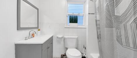A bathroom with a toilet, sink, and shower.