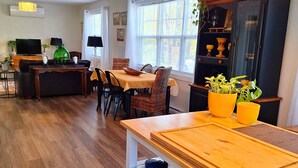 Una sala de estar moderna con comedor, piso de madera y un ventanal que proporciona luz natural.