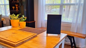 Un comedor con una mesa de madera, sillas y un aparador con objetos decorativos.