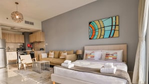 Et moderne hotelværelse med en stor seng, en sofa, et spiseområde og et køkken.