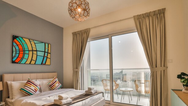 Et moderne hotelværelse med en stor seng, en balkon med udsigt over byen og et moderne kunstværk.