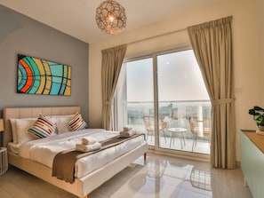 A modern hotel room with a large bed, a city view balcony, and a contemporary art piece. - Business Bay Classic Studio by Belvilla (Dubai)