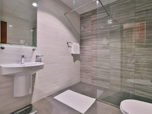 A modern bathroom with a glass shower enclosure, a white sink, and a toilet.